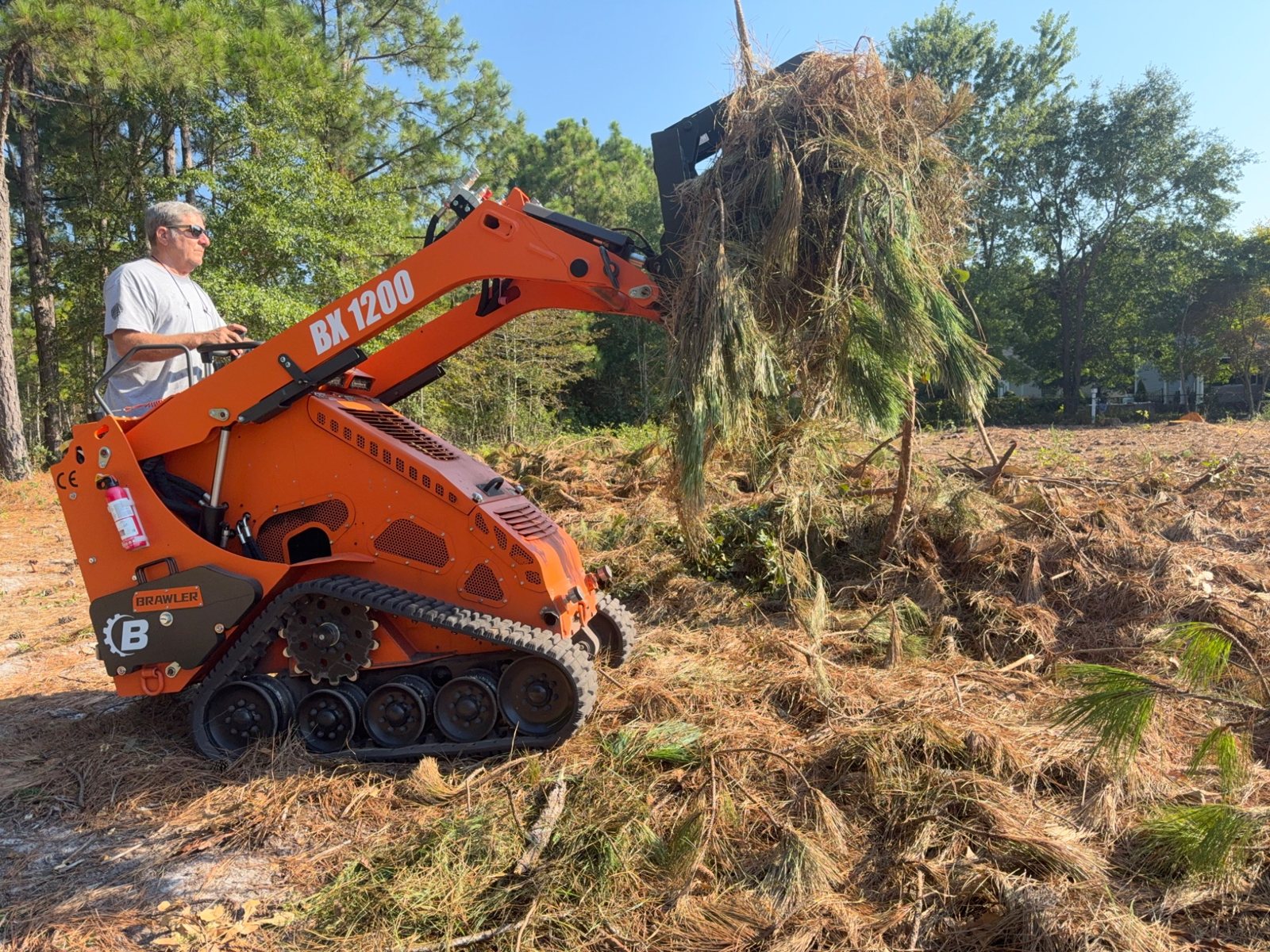Mini skid steer lifting a pile of brush and limbs